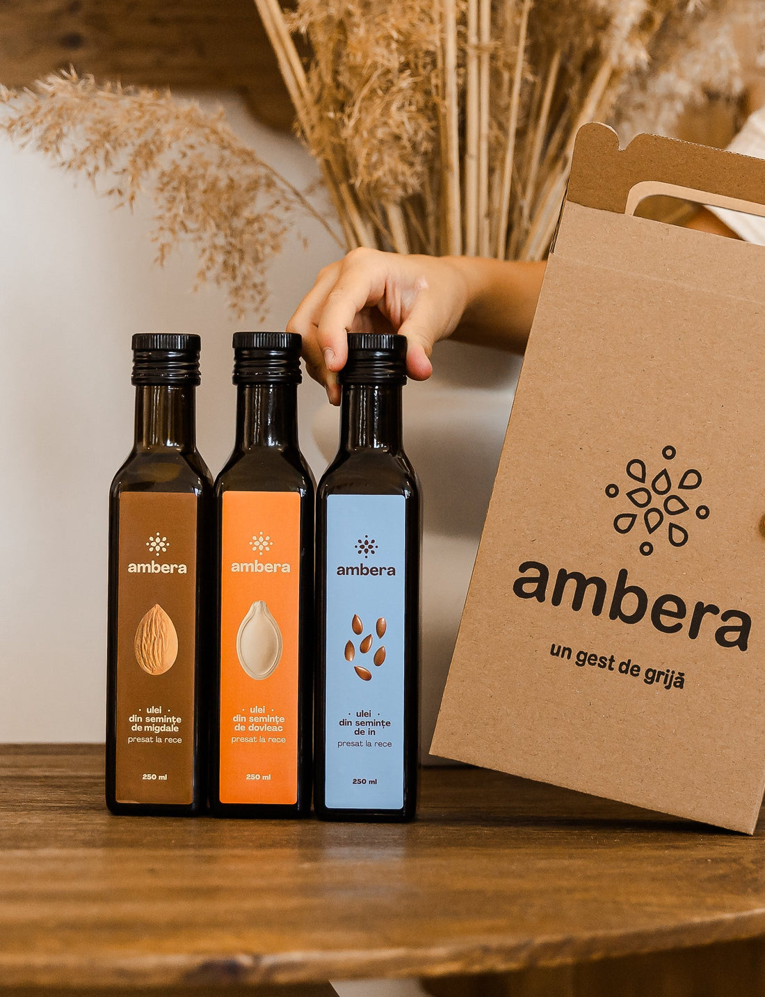 Trei sticle de ulei Ambera lângă cutia de cadou din carton